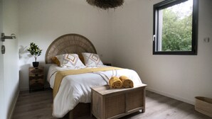 A bedroom with a bed, bedside tables, a window, and a view of greenery outside.