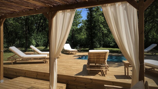 A wooden deck with a pool, surrounded by trees.