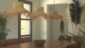 A dining area with a wooden table, six chairs, and three straw lampshades.