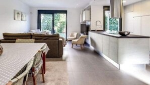 Un salon moderne comprenant un canapé, une table à manger et des chaises. Il y a également un coin cuisine avec une cuisinière et des placards.