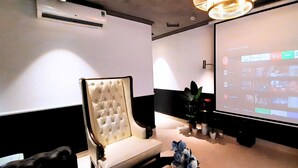 A conference room with a large projection screen displaying a presentation, a plush chair, and a small table with a plant. - A IN HOTEL DEL LUNA (Ho Chi Minh City)