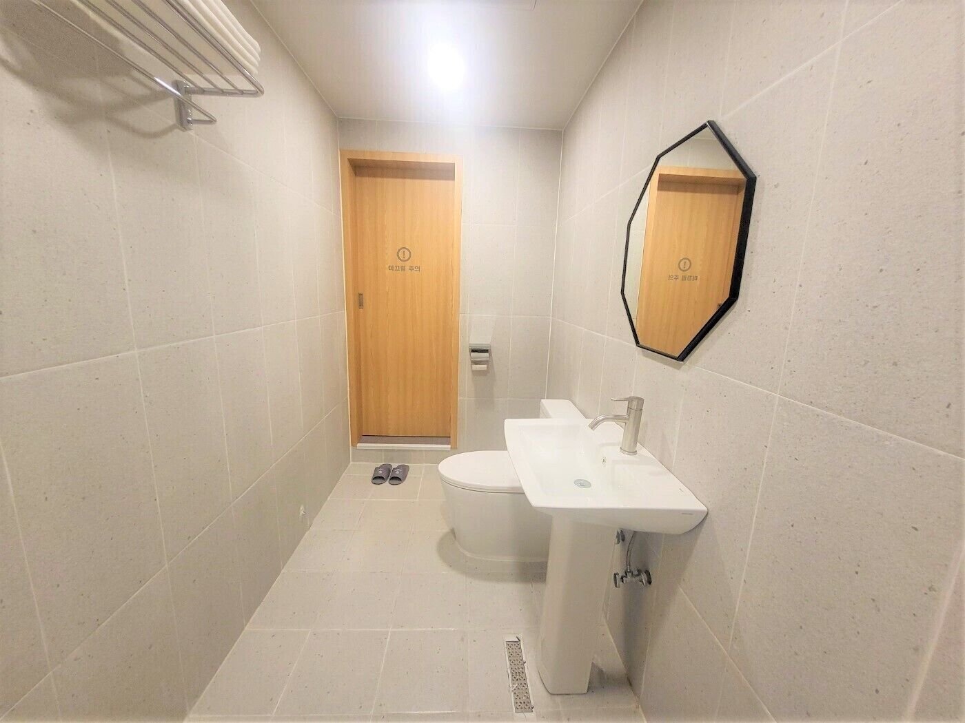 Un baño pequeño con inodoro, lavabo y ducha. Hay un perchero y un espejo en la pared.