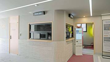 A front desk area with a sign, a vending machine, and a fire extinguisher.