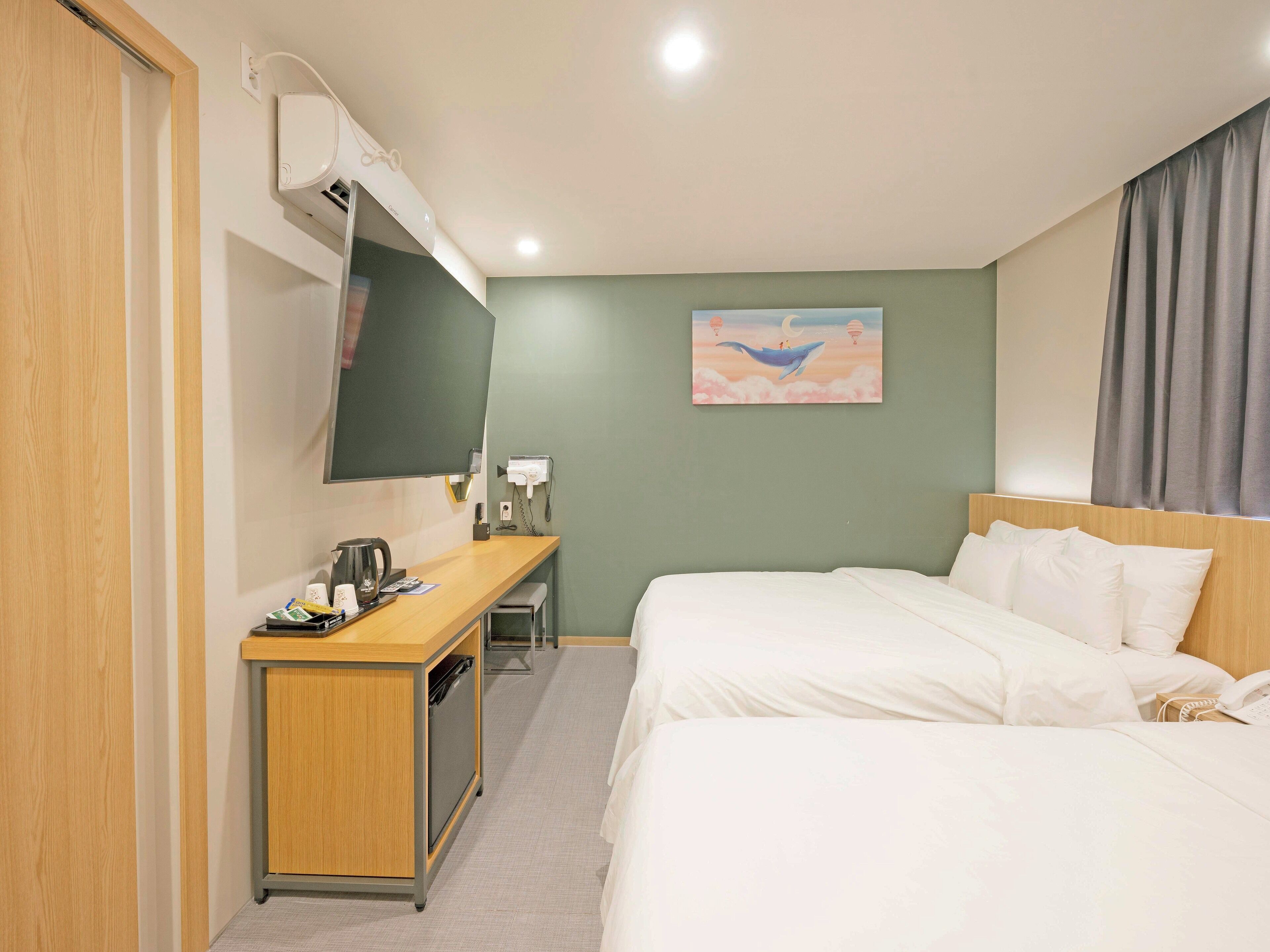 Une chambre d’hôtel avec un lit, un bureau, une chaise, un téléphone, une machine à café et un tableau au mur.