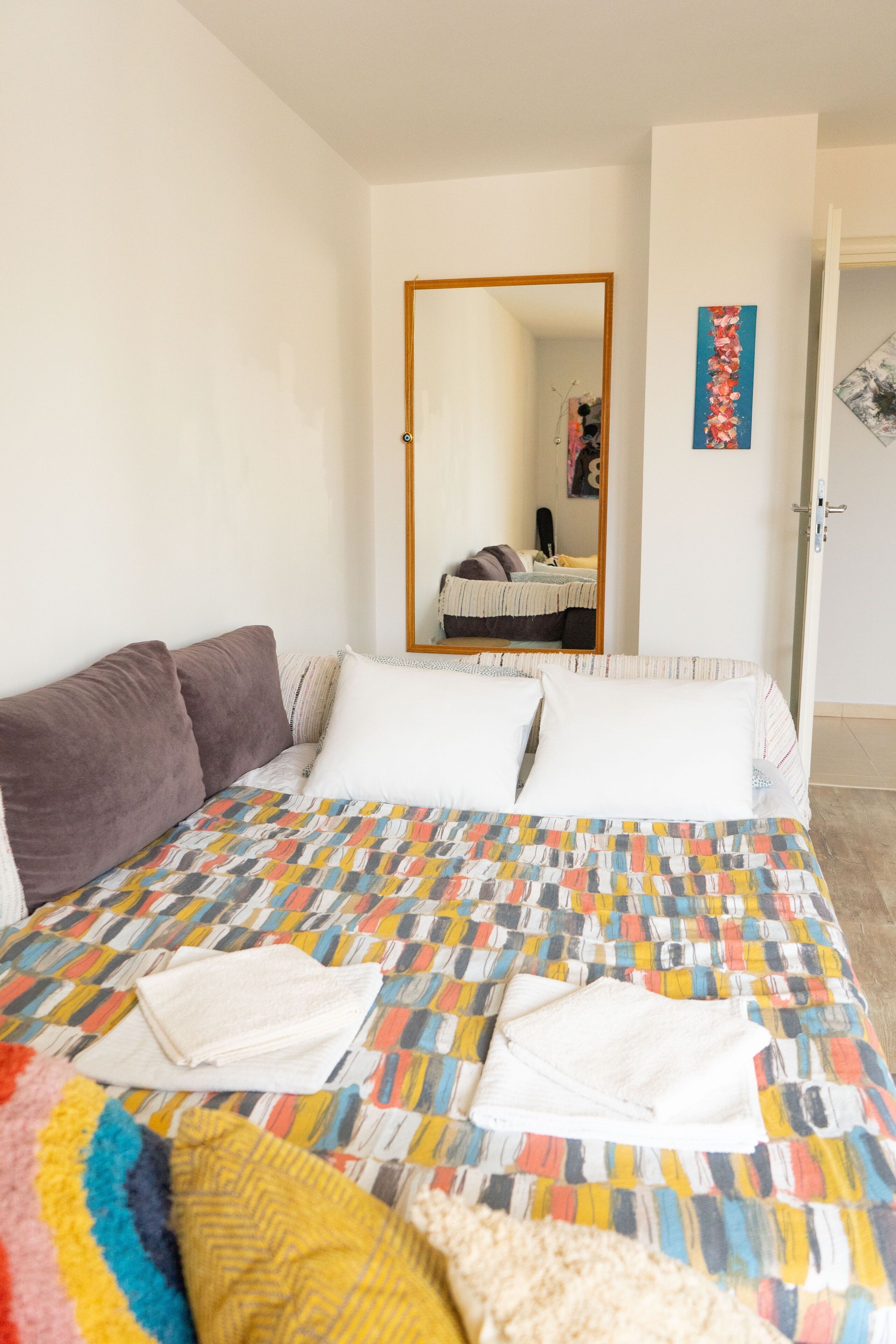 Une chambre à coucher avec un lit, des oreillers, un miroir et une porte.