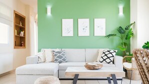 Uma sala de estar moderna com um sofá modular cinza claro, uma mesa de centro de madeira e uma parede verde de destaque.