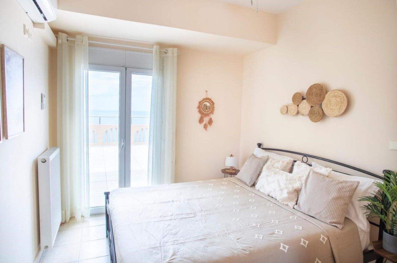 Een slaapkamer met een bed, een nachtkastje, een aan de muur bevestigde dromenvanger en uitzicht op de omgeving via een schuifdeur.