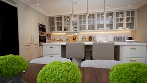 A modern kitchen with white cabinetry, a central island, and pendant lighting. - Beautiful 4-bed Flat in Mayfair (London)