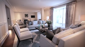 Relax in the living room, featuring a central seating area with a sofa and armchairs, fireplace, and flat-screen TV.