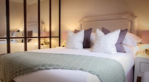 Relax in a cozy space with a large bed, pillows, and a nightstand with a lamp.