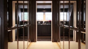 Enter a stylish hallway with glass doors leading to adjacent rooms and a modern kitchen area.