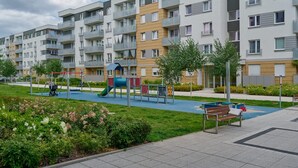 A modern apartment building with balconies, a playground, and a well-maintained garden. - Comfortable Apartment with Parking | Balcony | Air Conditioning (Wroclaw)