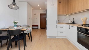 Una cocina moderna con armarios blancos, una encimera de madera y un horno negro.