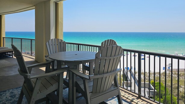 A balcony with a table and chairs overlooking a beach. - Bella Riva 409 4 bedroom Beachfront (Fort Walton Beach)