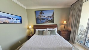 A neatly made bed with a patterned bedspread, two bedside lamps, and two framed coastal landscape paintings on the walls. - Bella Riva 409 4 bedroom Beachfront (Fort Walton Beach)