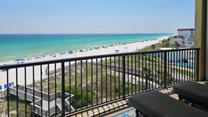 A balcony with a view of a beach, a pool, and a building in the background. - Bella Riva 409 4 bedroom Beachfront (Fort Walton Beach)