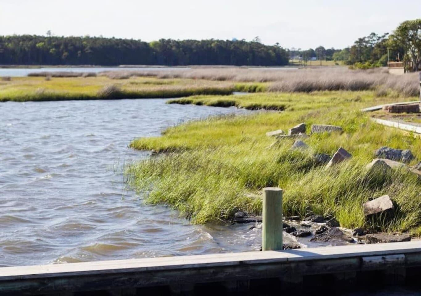 Een rustige rivier met grasoevers en een houten looppad.