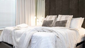 Ein Schlafzimmer mit Bett, Vorhängen und einer dunkel gestrichenen Wand.