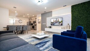 Ein modernes Wohnzimmer mit einer Couch, Sesseln, einem Couchtisch und einem Fernseher.