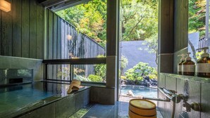 A spa area with a hot tub, wooden barrel, and a view of a garden through large windows. - besshoonsen midoriya (Ueda)