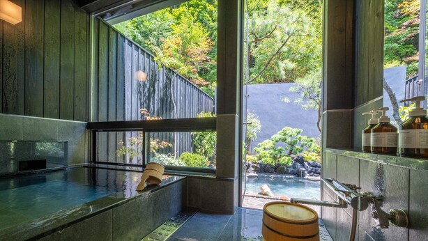 A spa area with a hot tub, wooden barrel, and a view of a garden through large windows. - besshoonsen midoriya (Ueda)