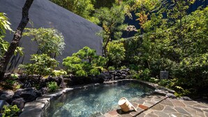 A hot tub surrounded by lush greenery and a stone pathway. - besshoonsen midoriya (Ueda)