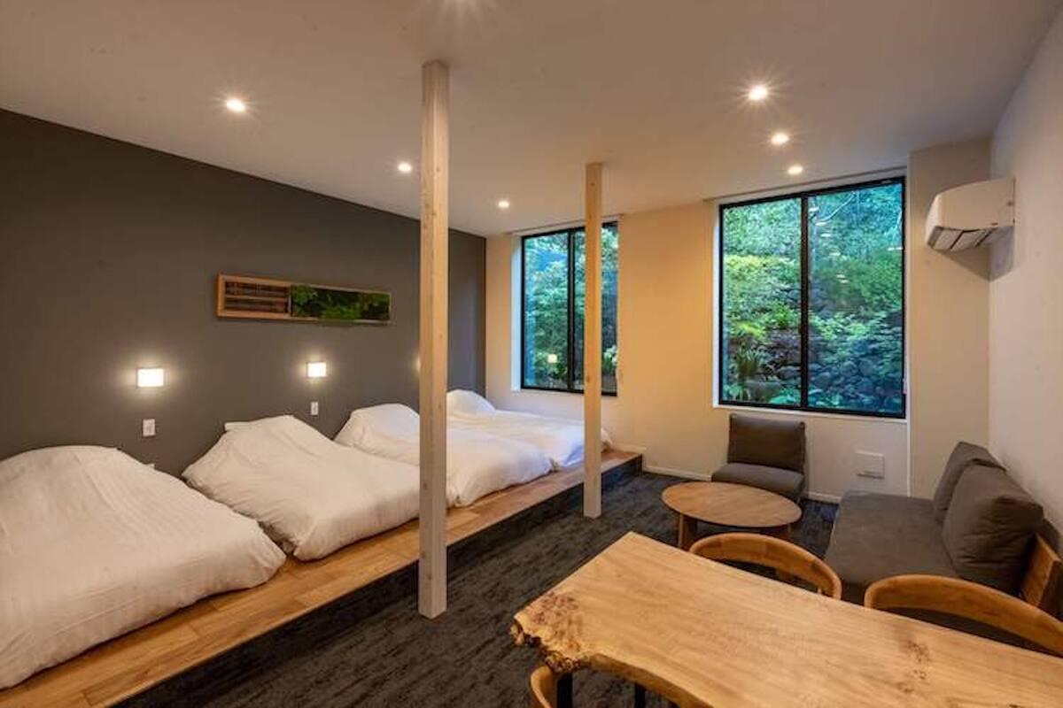Ein modernes Zimmer mit zwei Betten, einem Esstisch und einer Couch.