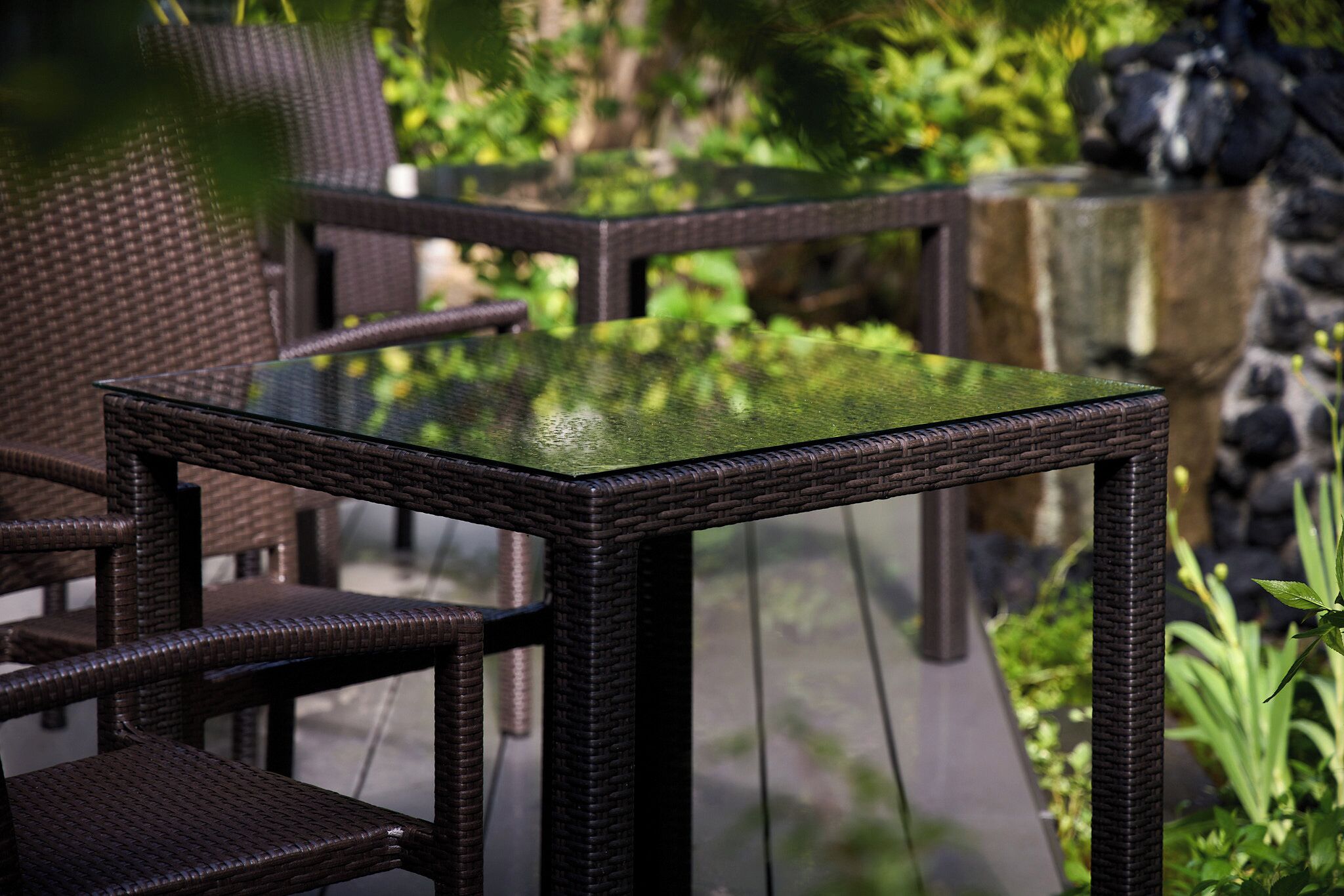 A glass-top table with wicker chairs in an outdoor setting.