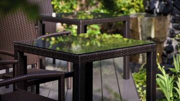 A glass-top table with wicker chairs in an outdoor setting.