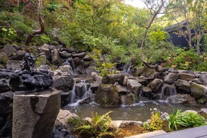 Un jardín sereno con un estanque de peces koi, una cascada pequeña y un tradicional torii japonés.
