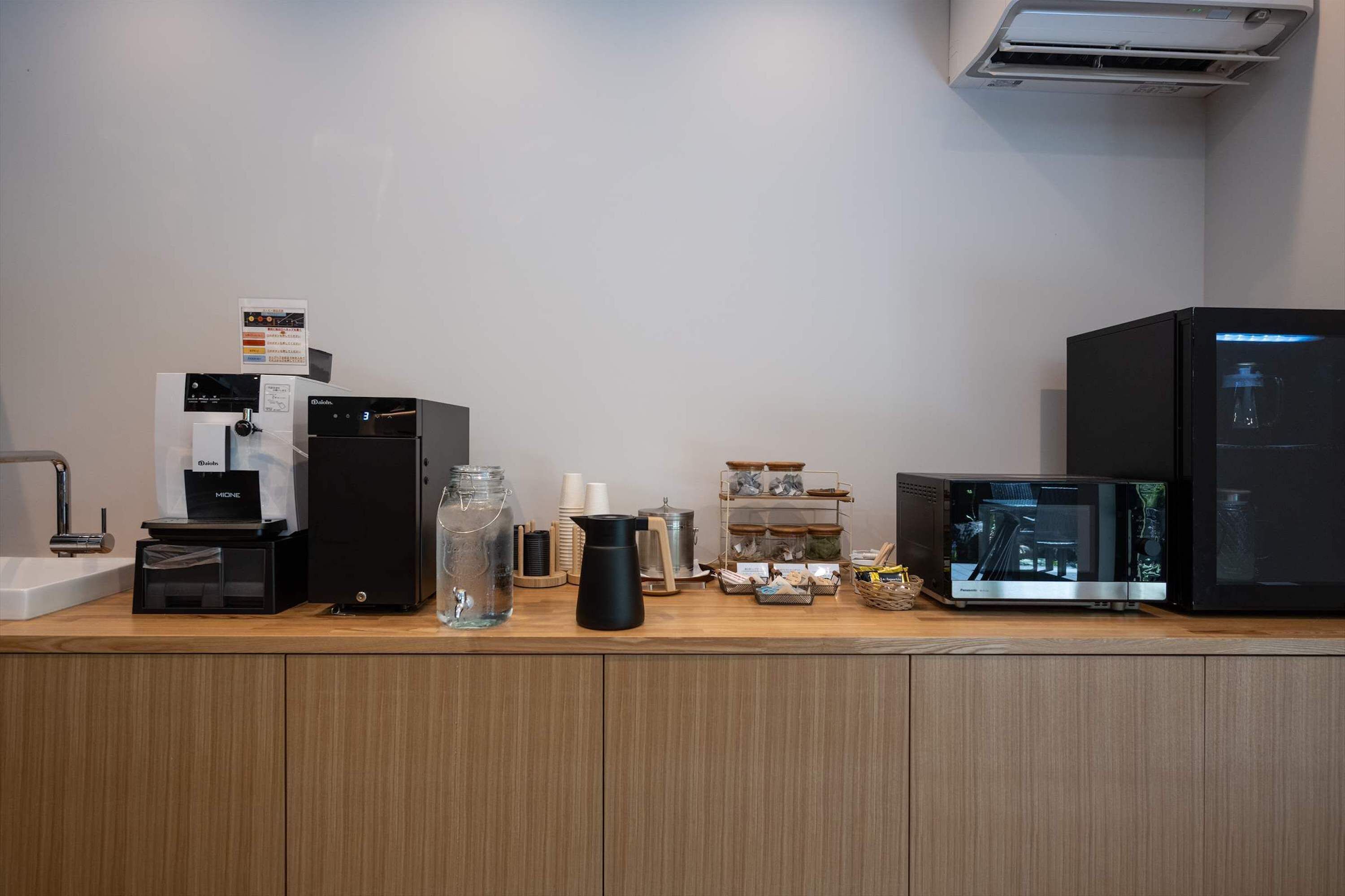 Un espace dédié au café, équipé d’une machine à café, d’un distributeur d’eau, d’un présentoir de tasses à café et d’un moulin à café.