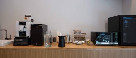 Eine Kaffeestation mit Kaffeeautomaten, Wasserspender, Kaffeetassen und einer Kaffeemühle.