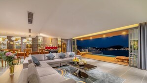 Un salon moderne avec un grand canapé, une table basse et une vue sur la ville la nuit.
