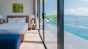 Une chambre d’hôtel moderne avec un grand lit, une petite table, une chaise et une vue sur l’océan.