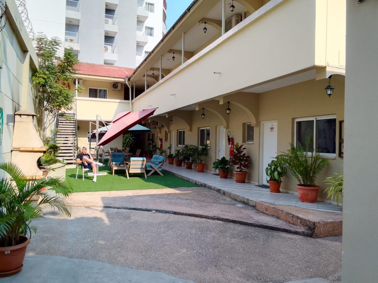 Un cortile d'hotel con posti a sedere all'aperto, piante in vaso e una scala che conduce all'ingresso.