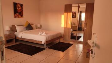 A bedroom with a bed, nightstands, a ceiling fan, a painting, and a mirror.