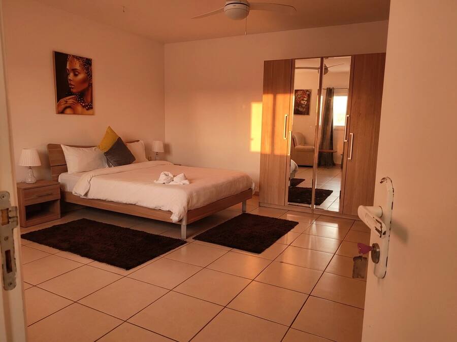 A bedroom with a bed, nightstands, a ceiling fan, a painting, and a mirror.