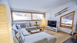 Una sala de estar moderna con un sofá modular, un televisor y una chimenea.