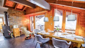 Interior rústico de madera con una mesa de comedor lista para cuatro personas, rodeada de sillas de mimbre.