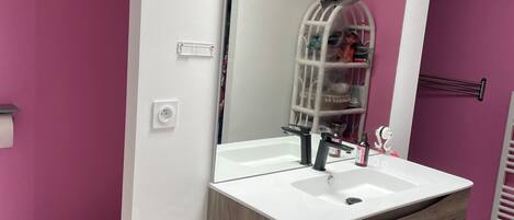 Une salle de bain avec un lavabo blanc, un meuble-lavabo en bois et un miroir.