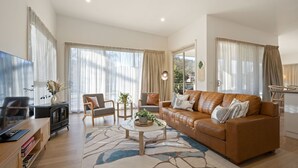 A modern living room with a leather sofa, a wooden coffee table, and a TV on a wooden stand. - Brothers of Bright.. (Bright)