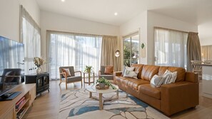 Relax in this stylish living room with a comfortable sofa, coffee table, and entertainment unit, offering a view of the outdoors.