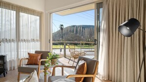 Enjoy breathtaking mountain views from the comfort of this living room, featuring a large sliding glass door and a cozy outdoor space.