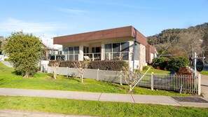 A modern two-story building with a flat roof, large windows, and a white picket fence. - Brothers of Bright.. (Bright)