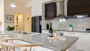 A modern kitchen with a central island, stainless steel appliances, and a large window. - Brothers of Bright.. (Bright)