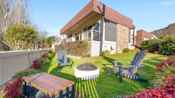Relax in a serene outdoor space with a fire pit, Adirondack chairs, and a dining area.