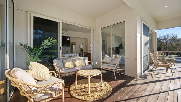 A covered outdoor seating area with wicker furniture and a woven rug. - Brothers of Bright.. (Bright)