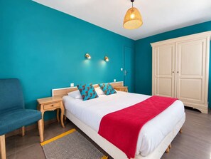 A hotel room with a bed, a nightstand, a chair, a wardrobe, and a patterned rug.