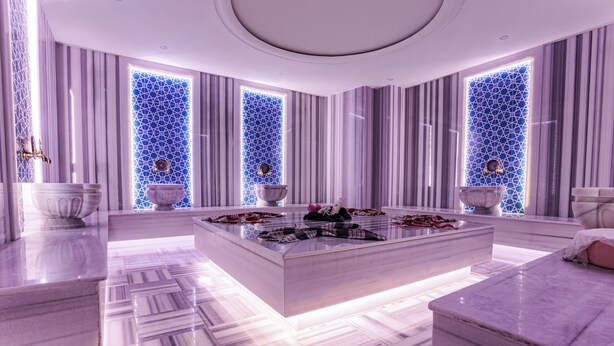 A luxurious bathroom with a marble floor, large white bathtub, and a central island with a sink and decorative items. - Mays Royal Hotel (Istanbul)
