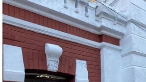 Edifici de maó vermell amb una porta blanca i un senyal amb el número 27.